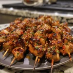 ['Close-up view of juicy Sweet Chili Chicken Skewers on a plate.', 'Side view of grilled chicken skewers glazed with sweet chili sauce.', 'Colorful presentation of tender chicken skewers drizzled with sauce.', 'Succulent chicken pieces on skewers, garnished and ready to serve.']