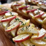 Close-up view of Apple Brie Crostini topped with sliced apples and honey.