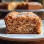 A moist slice of Apple Sauce Spice Cake with a creamy frosting, showcasing the spices and apple sauce.