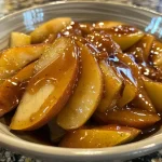 Close-up view of a bowl of cinnamon pear sauce with pieces of pear visible.