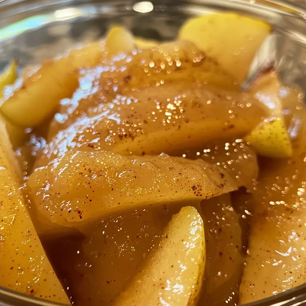Side perspective of rich, glossy cinnamon pear sauce in a glass container.