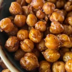 A close-up view of cinnamon roasted chickpeas in a bowl, glistening with sugar and spices.