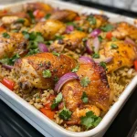 A close-up view of a high-protein chicken and rice casserole with golden-brown chicken thighs and colorful vegetables.