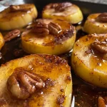 Close-up view of maple cinnamon baked apple slices topped with pecans.