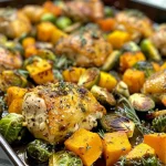 Close-up view of juicy sheet pan maple mustard chicken with roasted butternut squash and brussels sprouts.